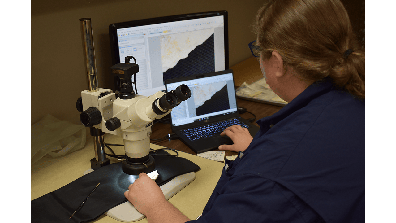 An archaeologist uses a high powered microscope and computer to analyze the edge of a stone tool