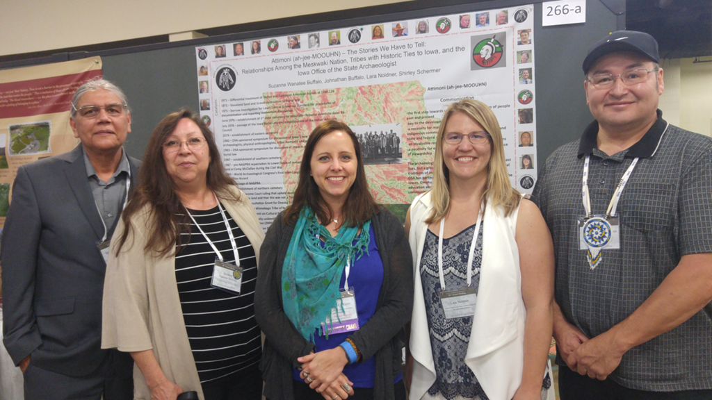 Five people post in front of a conference poster