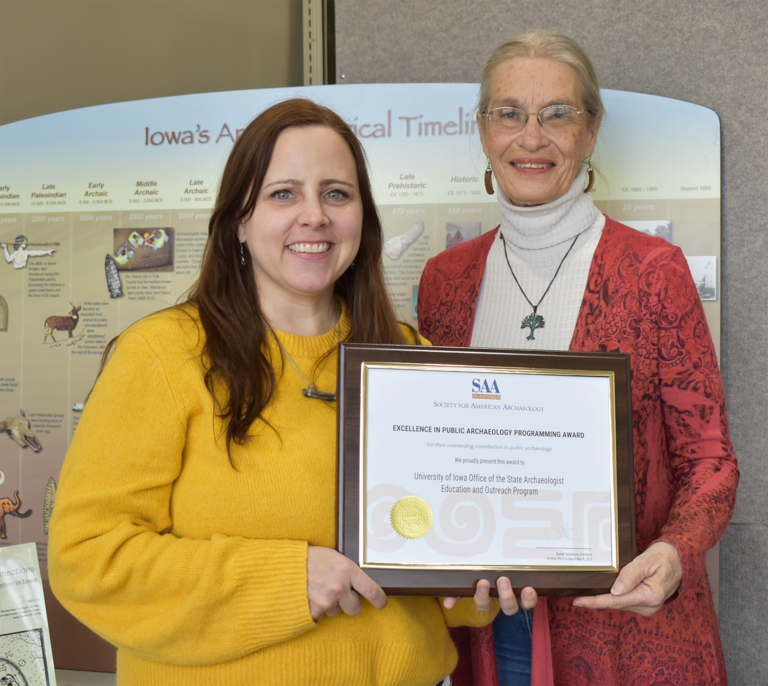 Elizabeth Reetz and Cherie Haury-Artz holding a plaque with a certificate that recognizes the award.