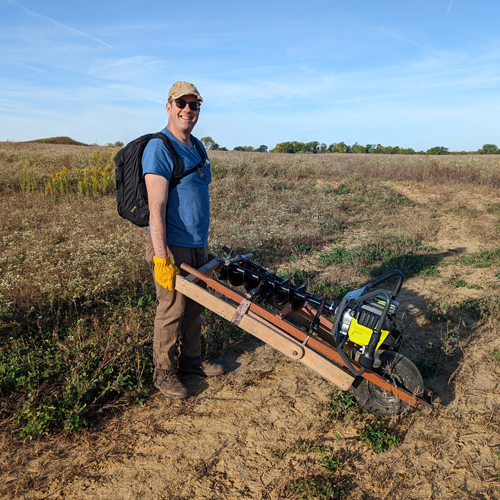 An archaeologist wheels a power auger on a cart