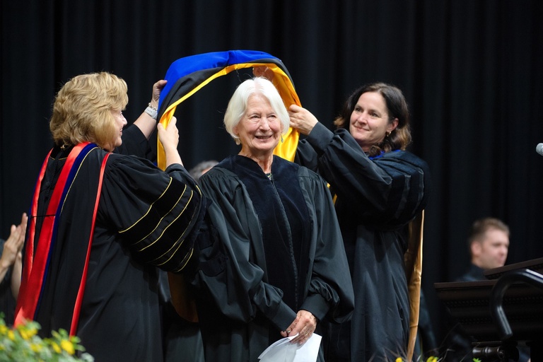 A woman getting hooding at a commencement ceremony