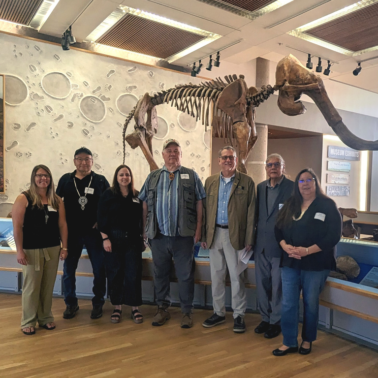 Seven people standing in front of a mammoth skeleton