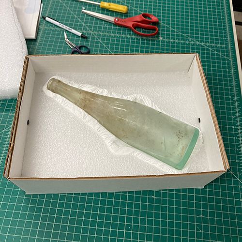 An old glass bottle in a custom fitted box