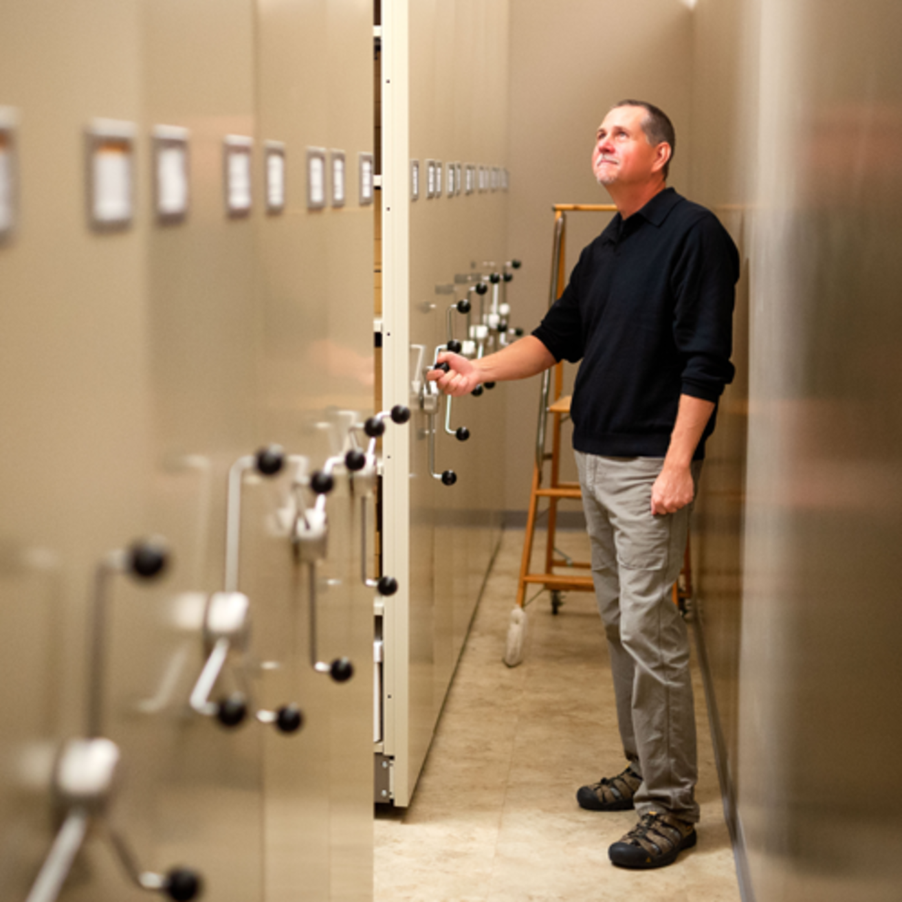 A man standing by moveable shelving in a curation repository