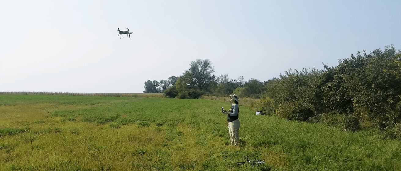 a women flying a drone in an open field