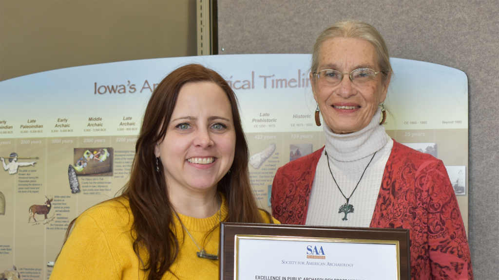 Elizabeth Reetz and Cherie Haury-Artz holding a plaque with a certificate that recognizes the award.
