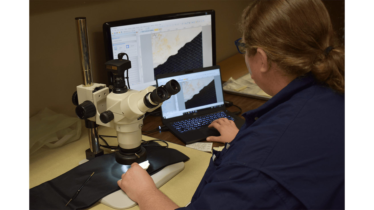 An archaeologist uses a high powered microscope and computer to analyze the edge of a stone tool